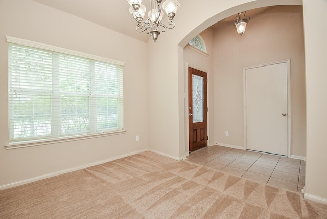 carpeted foyer with tile patterned floors, a notable chandelier, baseboards, and arched walkways