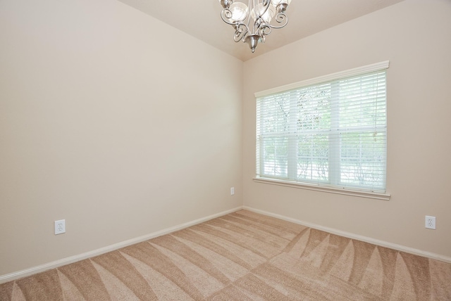 spare room with a notable chandelier, carpet flooring, and baseboards