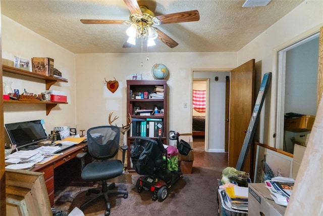 carpeted office with a textured ceiling and ceiling fan