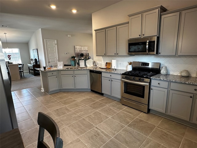 kitchen with a peninsula, a sink, gray cabinetry, appliances with stainless steel finishes, and tasteful backsplash