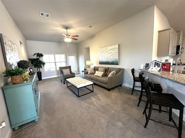 living room with visible vents, carpet floors, and a ceiling fan