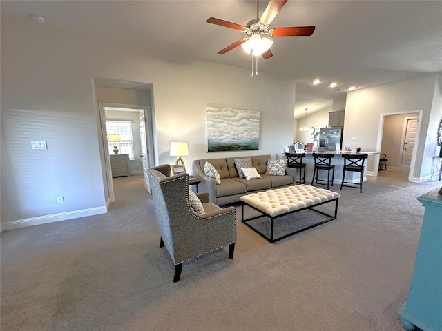 living area with baseboards, light colored carpet, and a ceiling fan