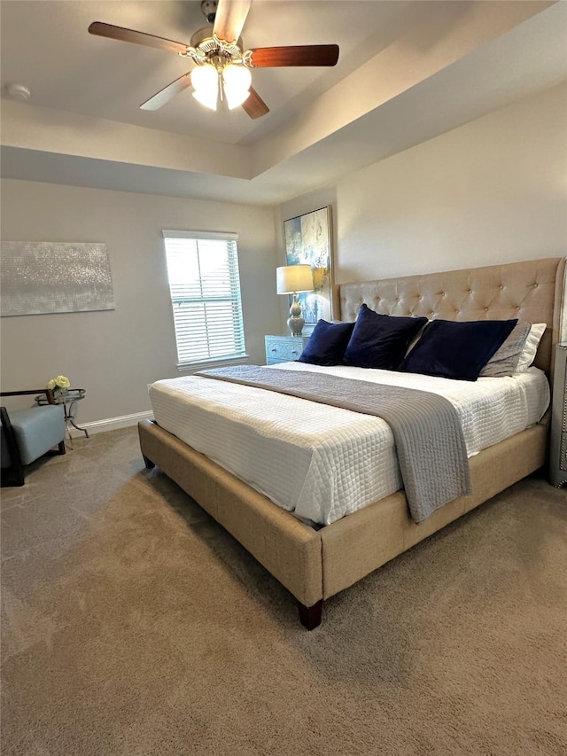 bedroom with a tray ceiling, baseboards, carpet, and a ceiling fan