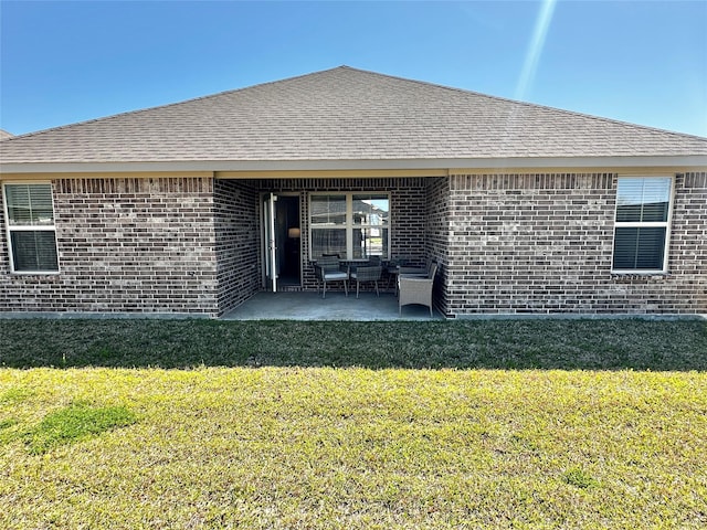 back of property featuring a patio area, a lawn, brick siding, and a shingled roof