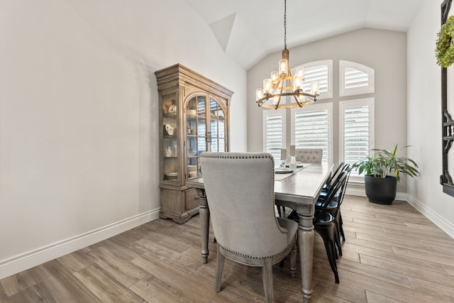 dining space with baseboards, light wood-type flooring, lofted ceiling, and an inviting chandelier