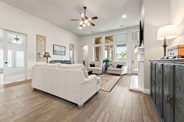 living room featuring wood finished floors, a ceiling fan, and arched walkways