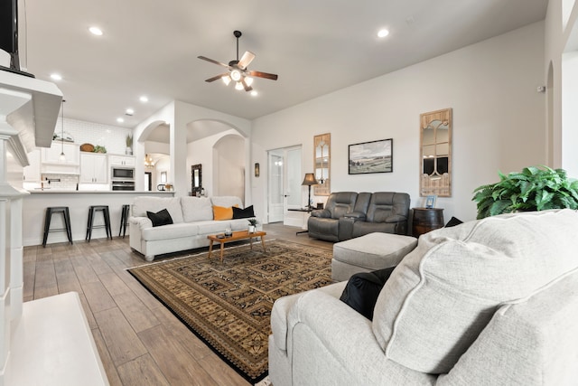 living room featuring recessed lighting, arched walkways, ceiling fan, and light wood finished floors