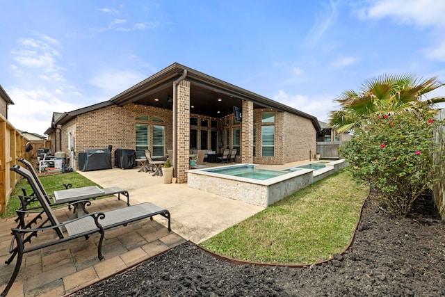 back of house with a patio area, a fenced backyard, an in ground hot tub, and brick siding