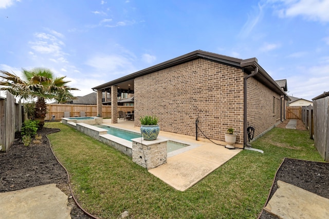 rear view of property with a patio area, a yard, a fenced backyard, and brick siding