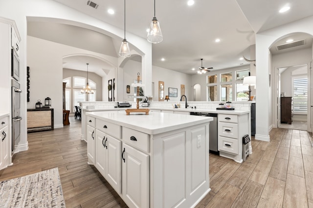 kitchen with light wood-type flooring, visible vents, a center island, arched walkways, and appliances with stainless steel finishes