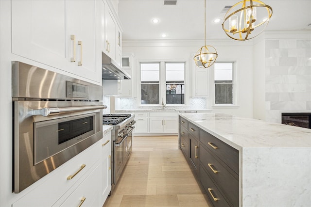 7527 Ciano Ln, Houston, TX 77055 - kitchen with a chandelier, appliances with stainless steel finishes, white cabinets, crown molding, and under cabinet range hood