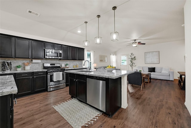 kitchen featuring visible vents, open floor plan, lofted ceiling, appliances with stainless steel finishes, and a sink