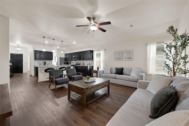 living room featuring dark wood finished floors, plenty of natural light, a ceiling fan, and visible vents