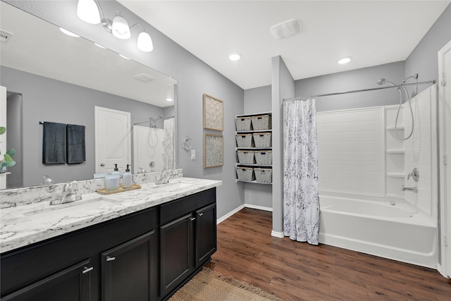 full bath with shower / bath combination with curtain, wood finished floors, baseboards, and a sink