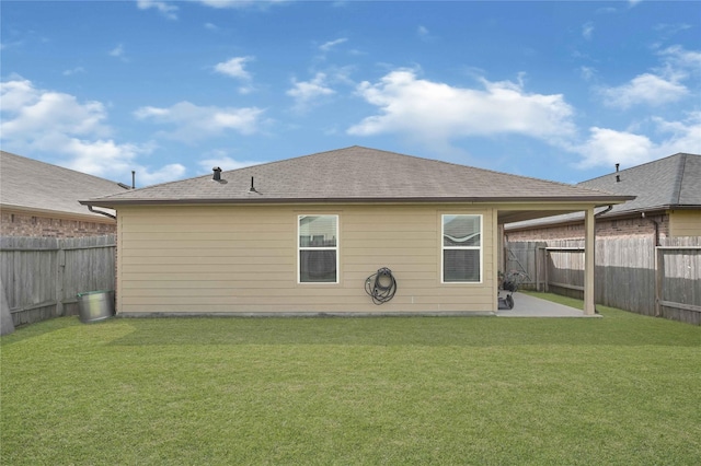 rear view of house featuring a lawn, roof with shingles, a fenced backyard, and a patio area