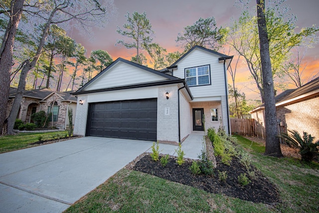 traditional-style home with brick siding, an attached garage, driveway, and fence