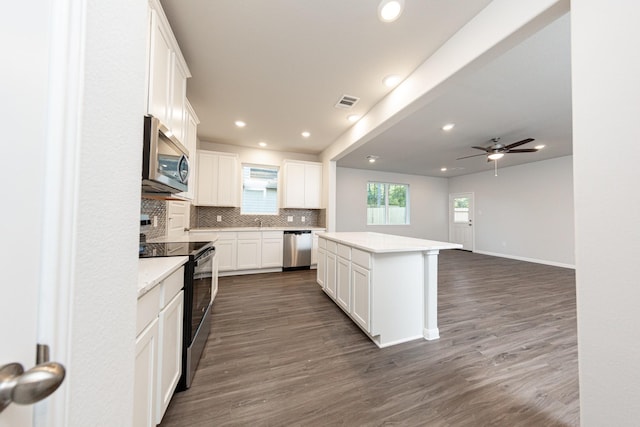 kitchen featuring recessed lighting, stainless steel appliances, dark wood-type flooring, a kitchen island, and decorative backsplash