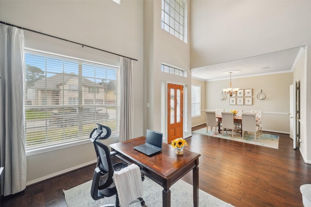 office space with ornamental molding, hardwood / wood-style flooring, a high ceiling, an inviting chandelier, and baseboards