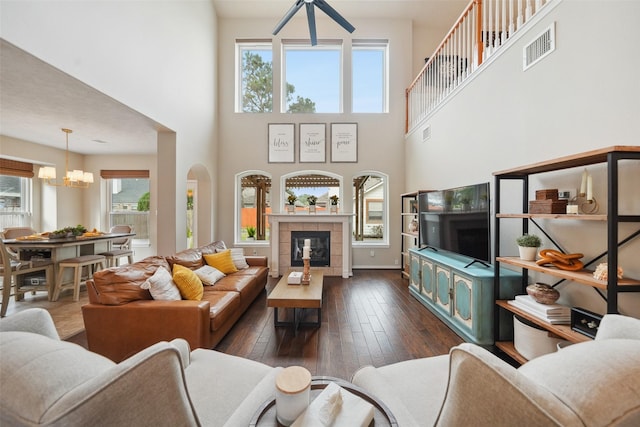 living room featuring visible vents, dark wood-style floors, a tile fireplace, and a chandelier