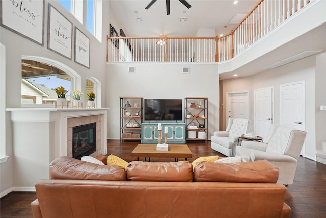 living area with visible vents, baseboards, dark wood finished floors, a fireplace, and a ceiling fan