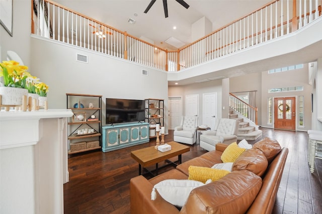 living room with stairs, visible vents, hardwood / wood-style floors, and a ceiling fan