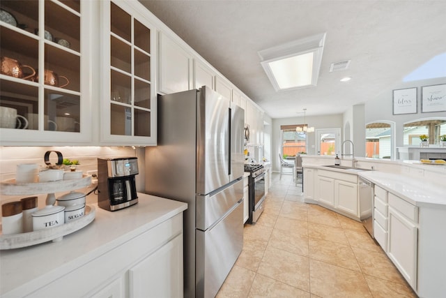 kitchen with light tile patterned floors, a sink, stainless steel appliances, glass insert cabinets, and white cabinetry