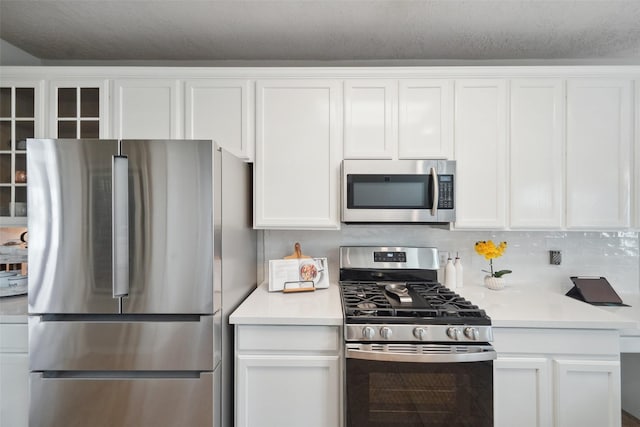 kitchen with decorative backsplash, light countertops, white cabinets, and stainless steel appliances