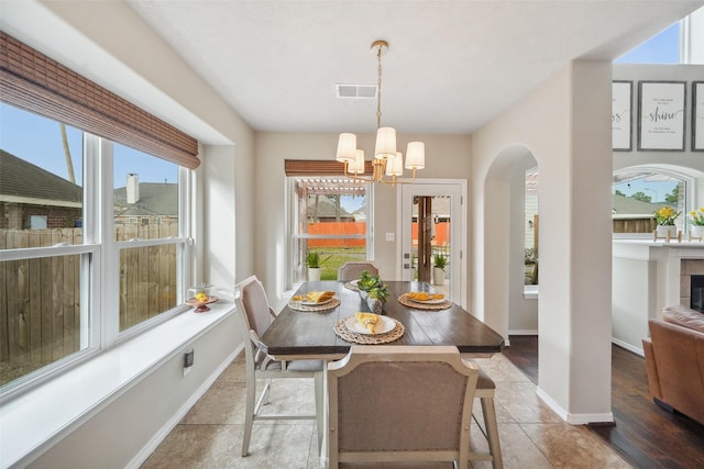 tiled dining space with visible vents, arched walkways, a notable chandelier, and baseboards