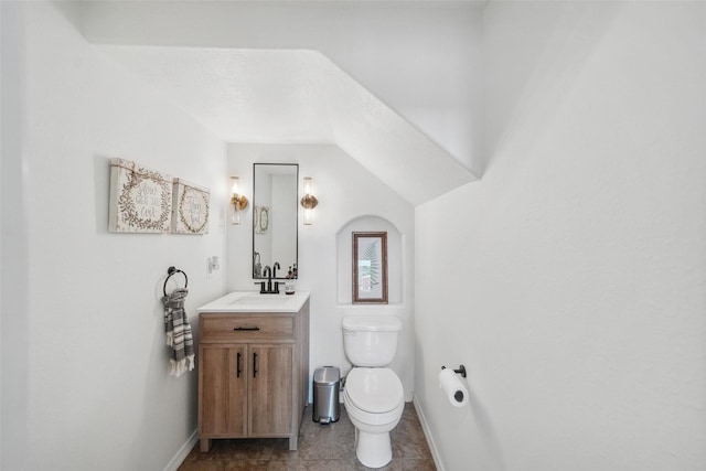 half bath with tile patterned flooring, toilet, vanity, and baseboards