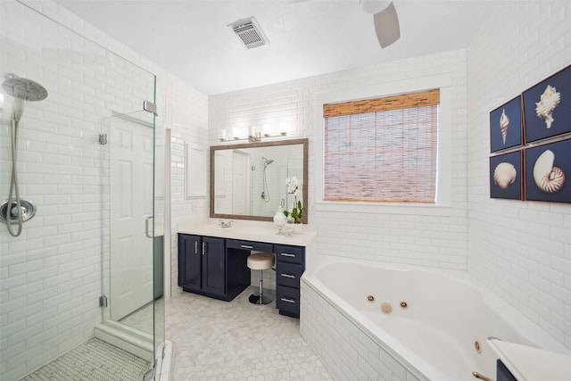 bathroom with visible vents, a shower stall, vanity, a tub with jets, and tile walls