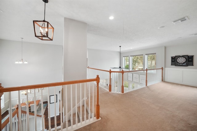 hallway featuring visible vents, an upstairs landing, recessed lighting, carpet floors, and an inviting chandelier