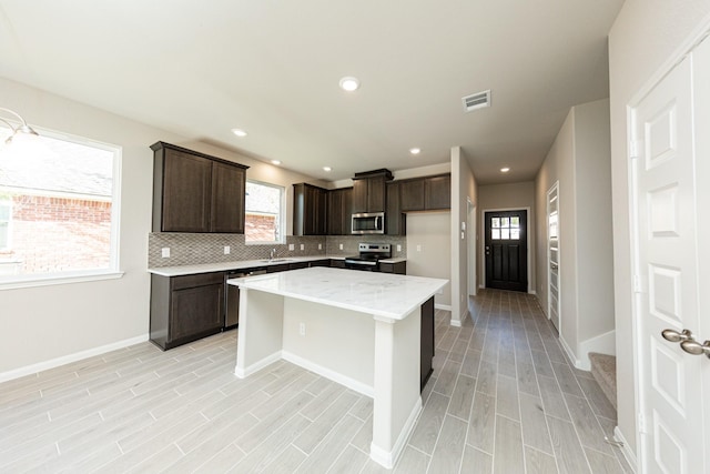 3714 Windswept Dr, Montgomery, TX 77356 - kitchen with stainless steel appliances, light wood-style flooring, dark brown cabinets, visible vents, and decorative backsplash