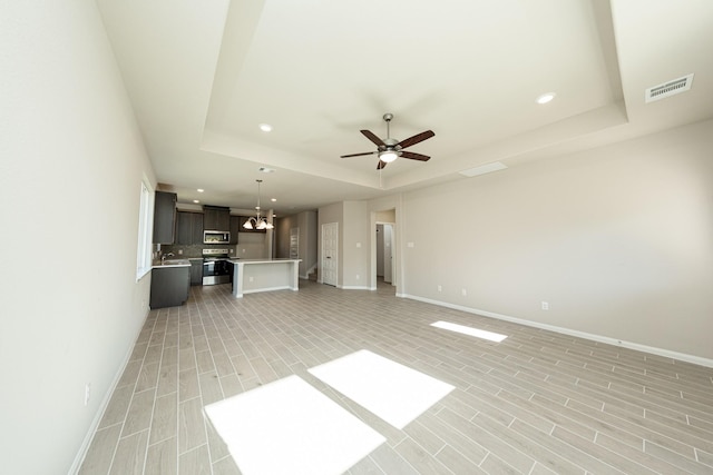3714 Windswept Dr, Montgomery, TX 77356 - unfurnished living room with baseboards, ceiling fan with notable chandelier, and a raised ceiling