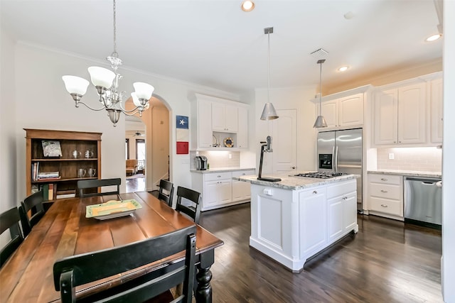 4303 Blossom St, Houston, TX 77007 - kitchen with arched walkways, appliances with stainless steel finishes, decorative backsplash, white cabinetry, and crown molding