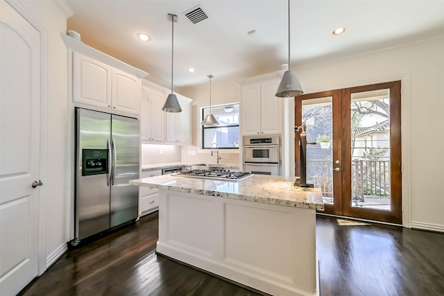 4303 Blossom St, Houston, TX 77007 - kitchen featuring stainless steel appliances, healthy amount of natural light, dark wood finished floors, white cabinetry, and recessed lighting