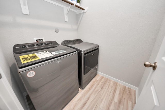 laundry room with baseboards, independent washer and dryer, laundry area, and light wood finished floors