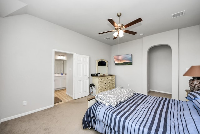 carpeted bedroom featuring visible vents, baseboards, vaulted ceiling, ensuite bath, and a ceiling fan