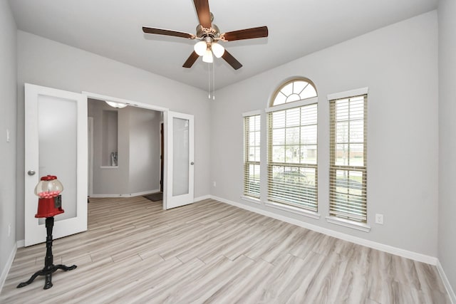 empty room featuring light wood-style flooring, a ceiling fan, and baseboards