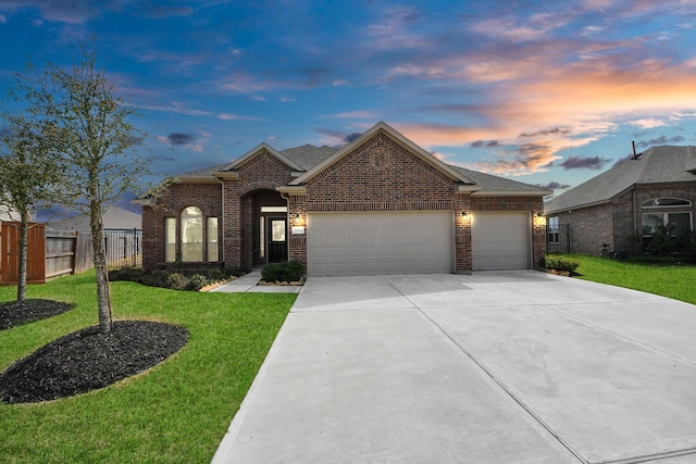 view of front of property featuring fence, an attached garage, a yard, concrete driveway, and brick siding