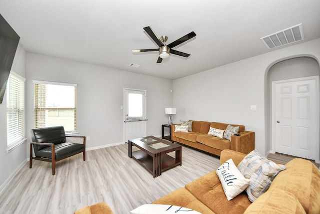 living area with visible vents, arched walkways, baseboards, and light wood finished floors