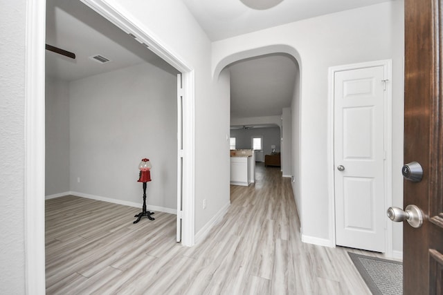 interior space featuring arched walkways, visible vents, light wood-style flooring, and baseboards