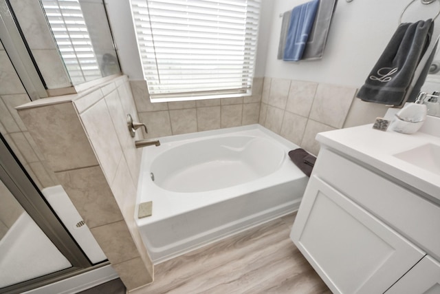 bathroom with vanity, a garden tub, wood finished floors, and a shower stall