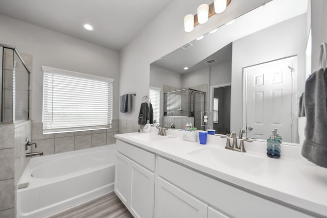 bathroom featuring a garden tub, a stall shower, visible vents, and a sink