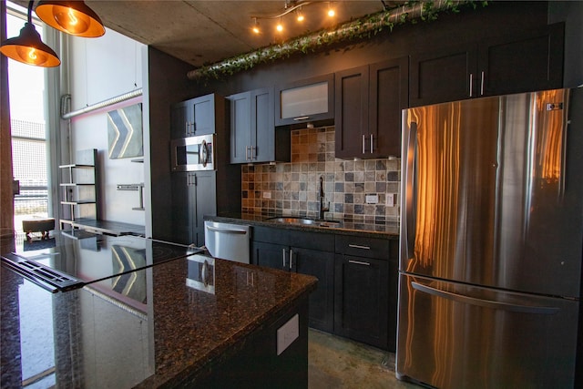 kitchen with tasteful backsplash, concrete floors, dark stone countertops, stainless steel appliances, and a sink