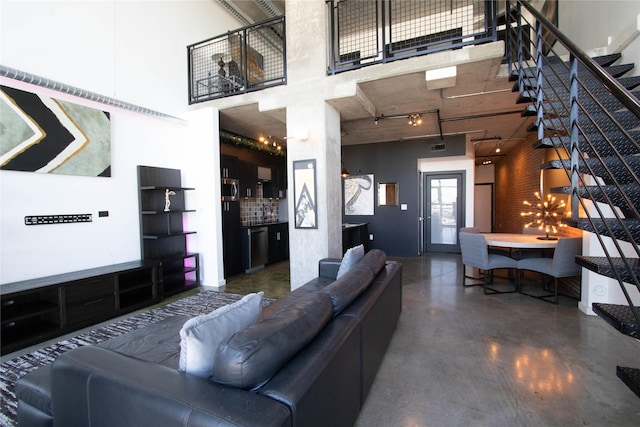 living room with track lighting, concrete floors, stairs, and a high ceiling