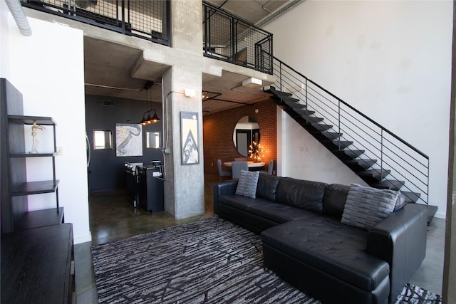 living room featuring concrete flooring, stairs, and a high ceiling