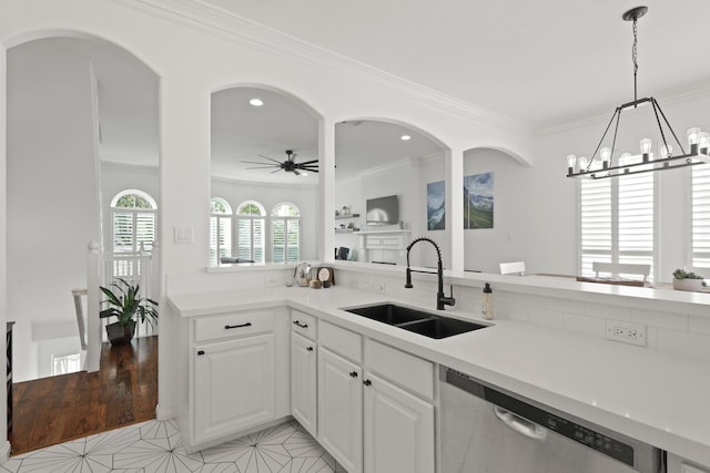 kitchen with ceiling fan with notable chandelier, ornamental molding, stainless steel dishwasher, and a sink