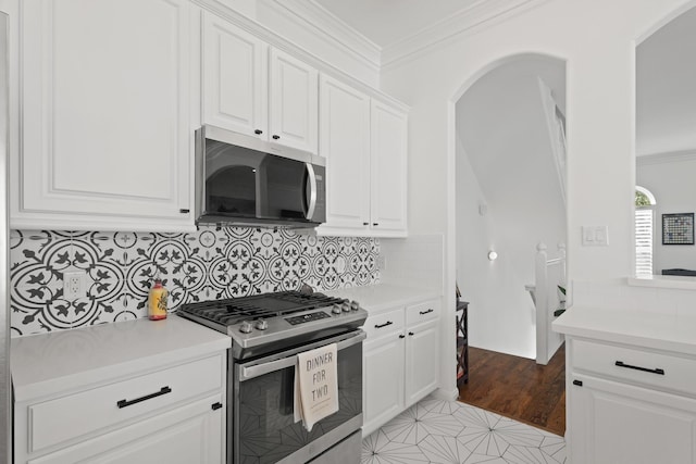 kitchen with crown molding, appliances with stainless steel finishes, light countertops, and arched walkways