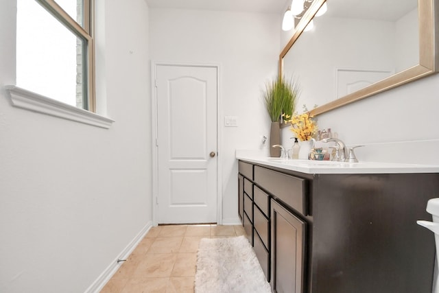 bathroom with tile patterned floors, baseboards, double vanity, and a sink