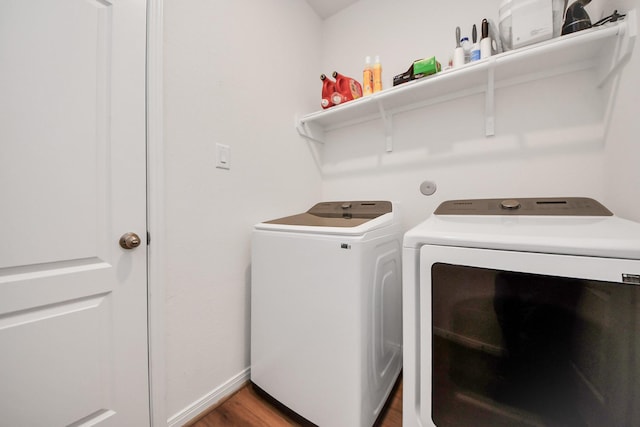 laundry area with washer and dryer, baseboards, wood finished floors, and laundry area